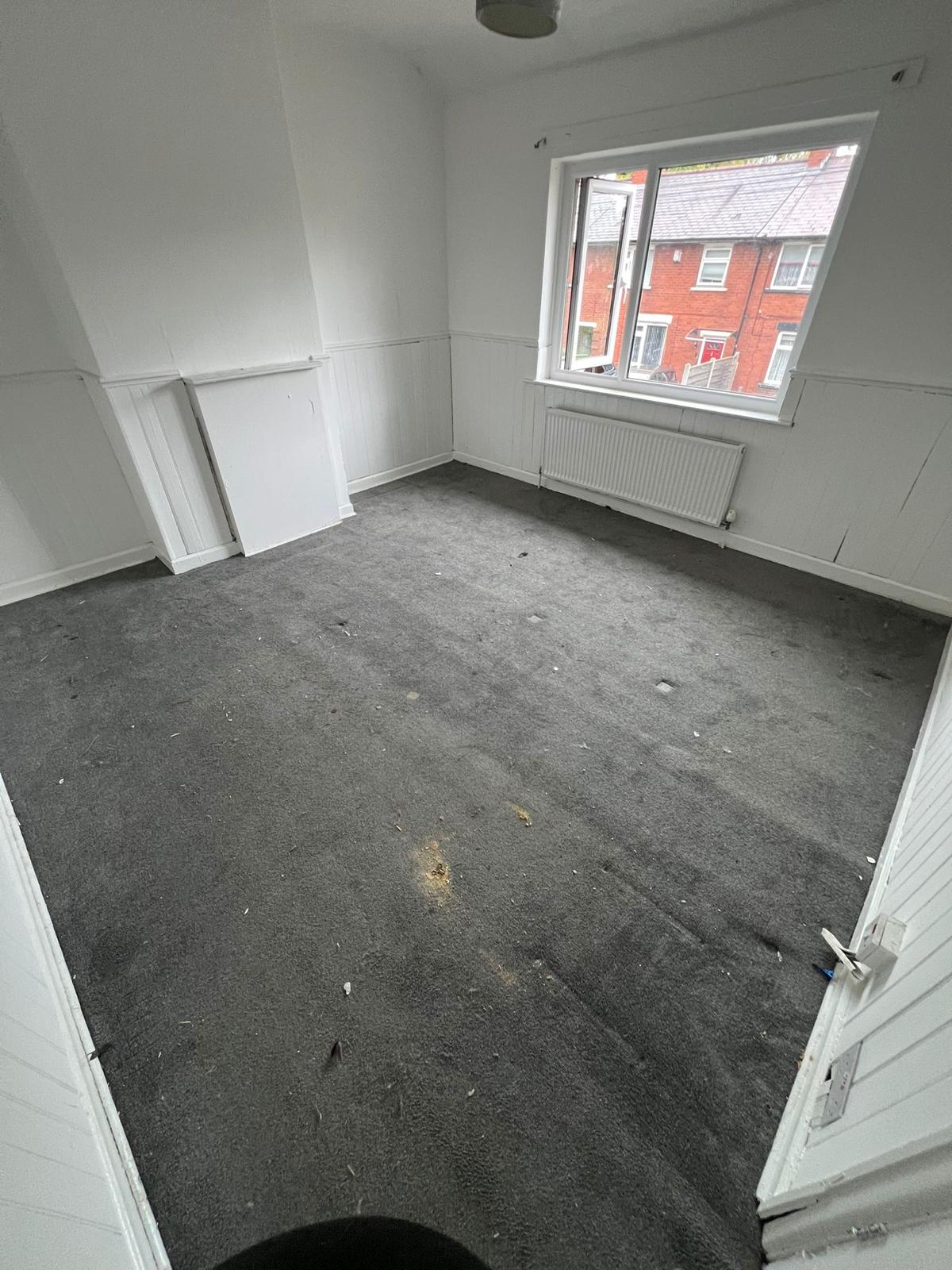 After: the same bedroom completely cleared, with empty carpet and clean walls.