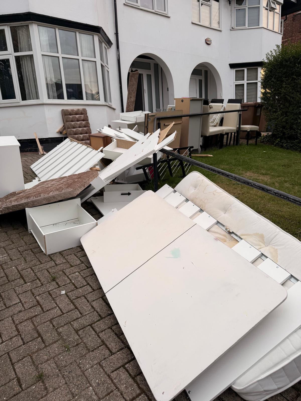 Before: a large pile of discarded furniture, mattresses, drawers and boards blocking the driveway of a white house in Manchester.