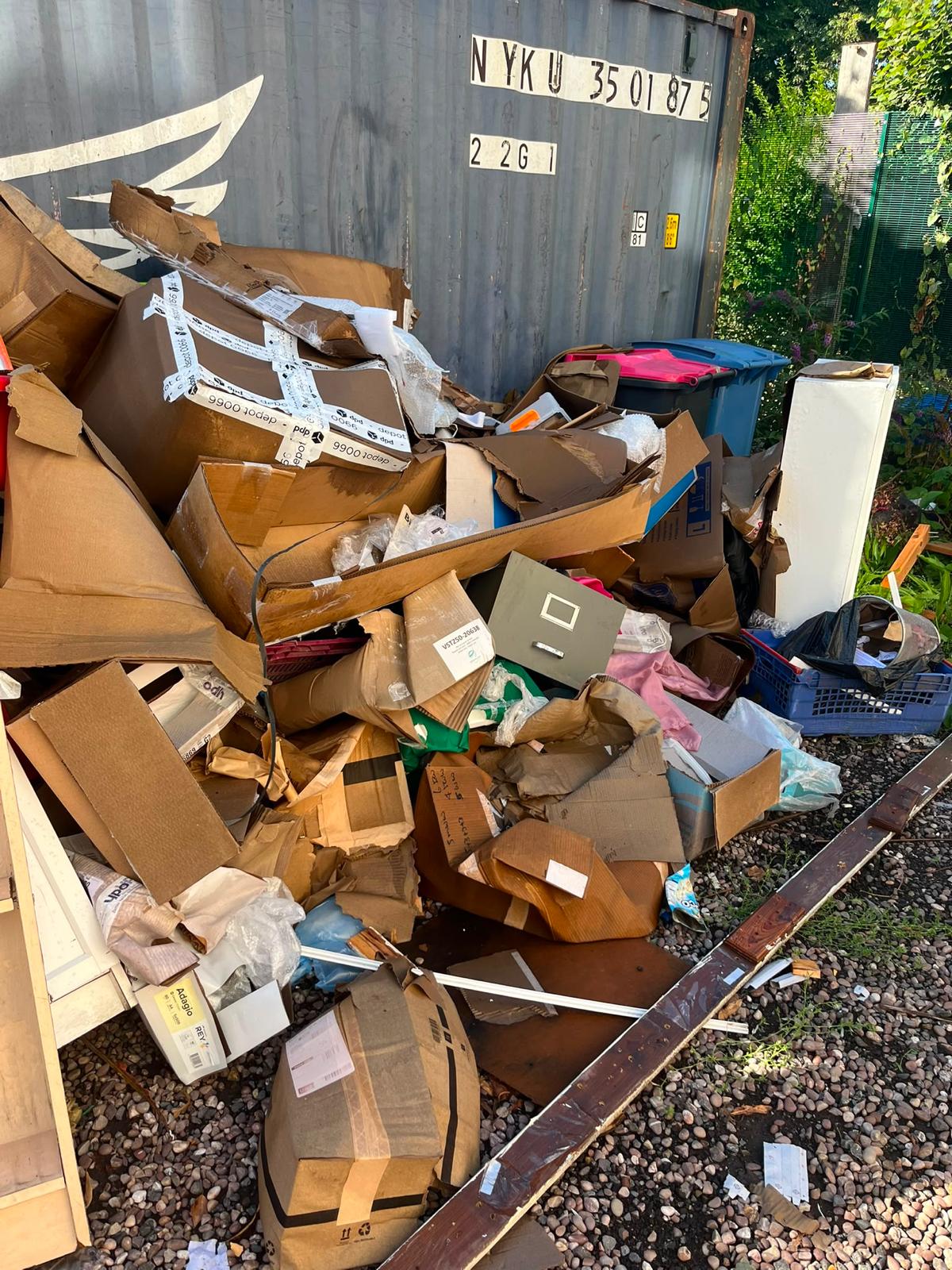 Before: a large pile of cardboard boxes, packaging and mixed waste in front of a shipping container on a commercial site.