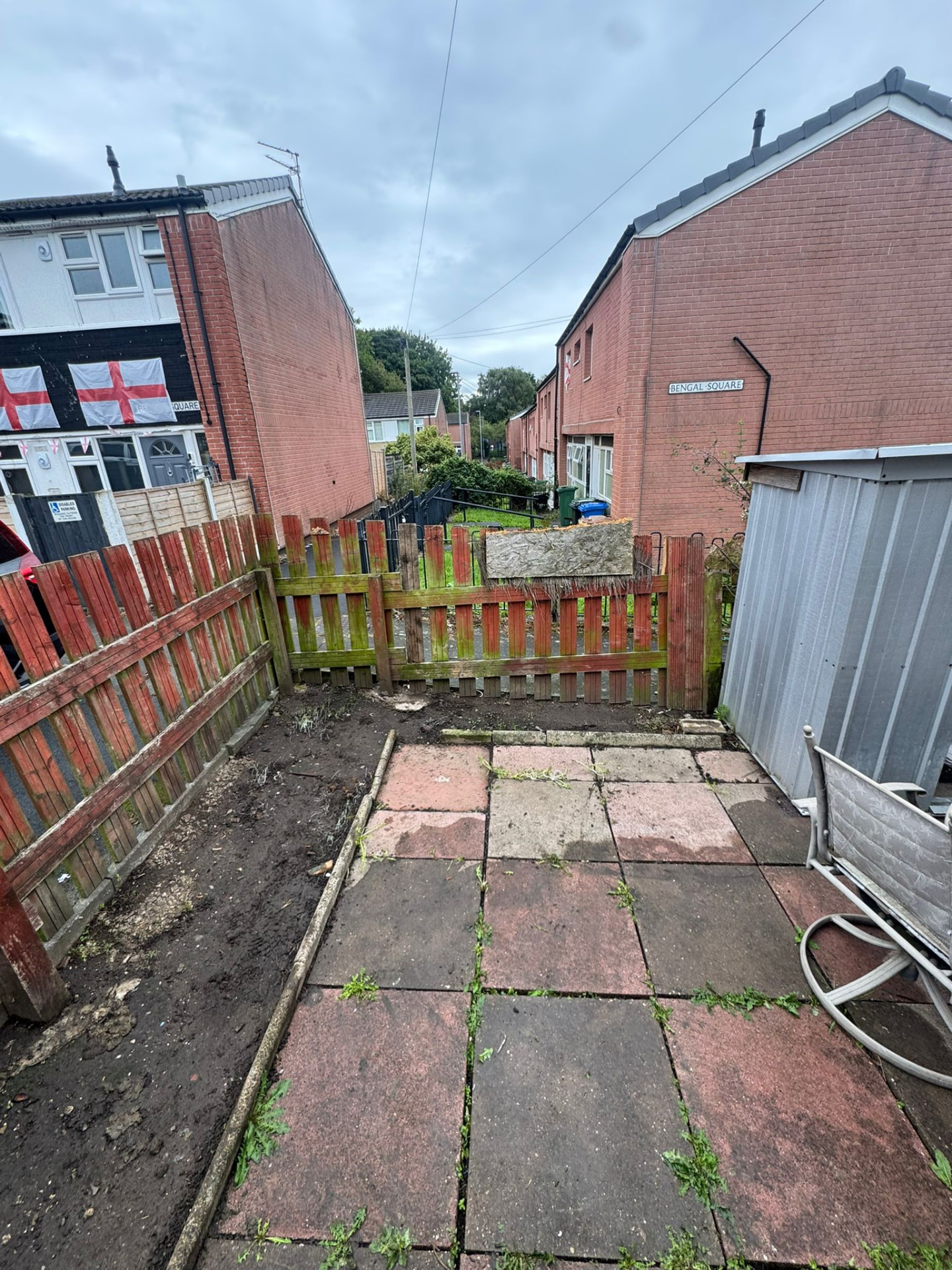 After: the same Ashton-under-Lyne patio fully cleared, showing clean paving stones, tidy borders and a shed.